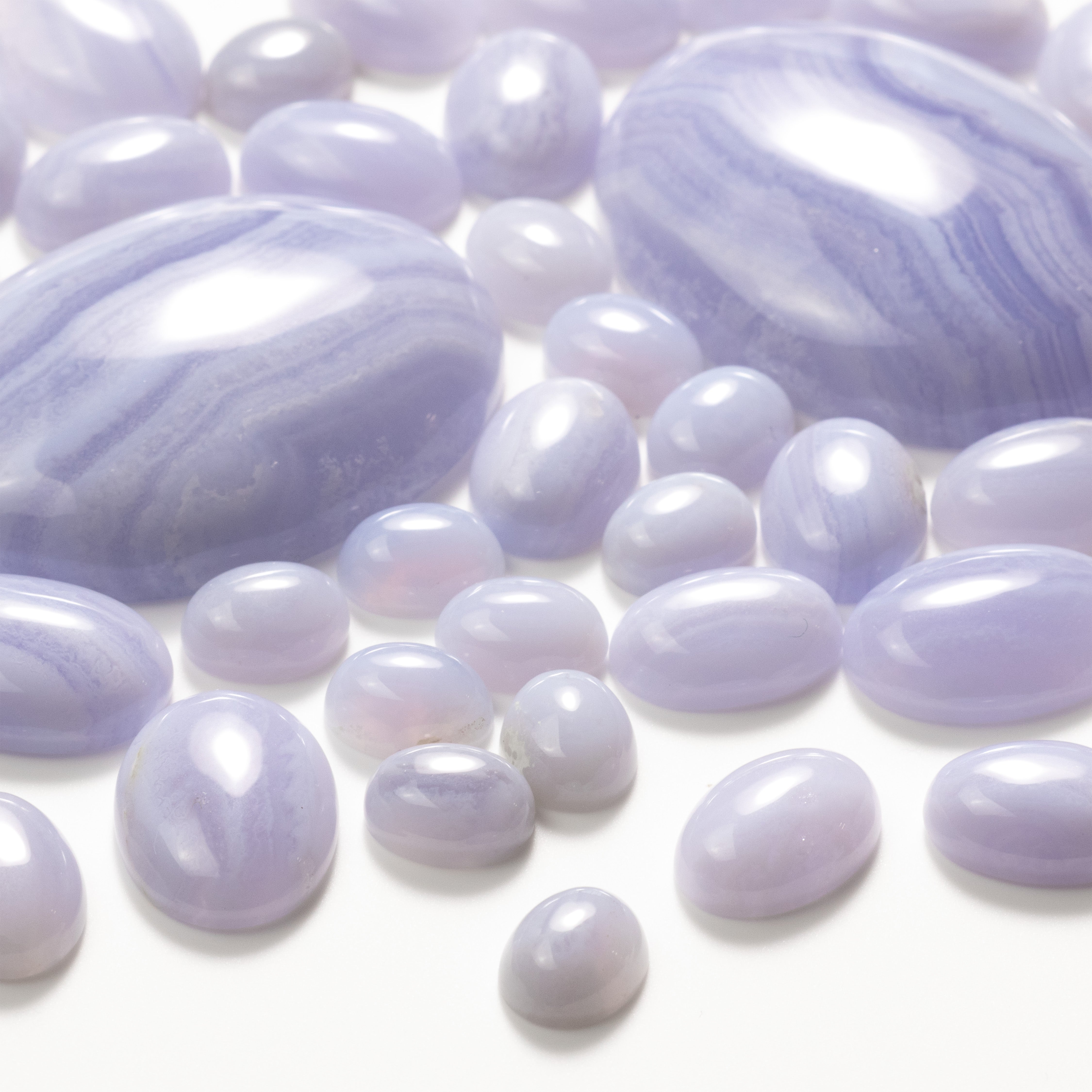 Blue lace agate oval cabochons scattered on a white background