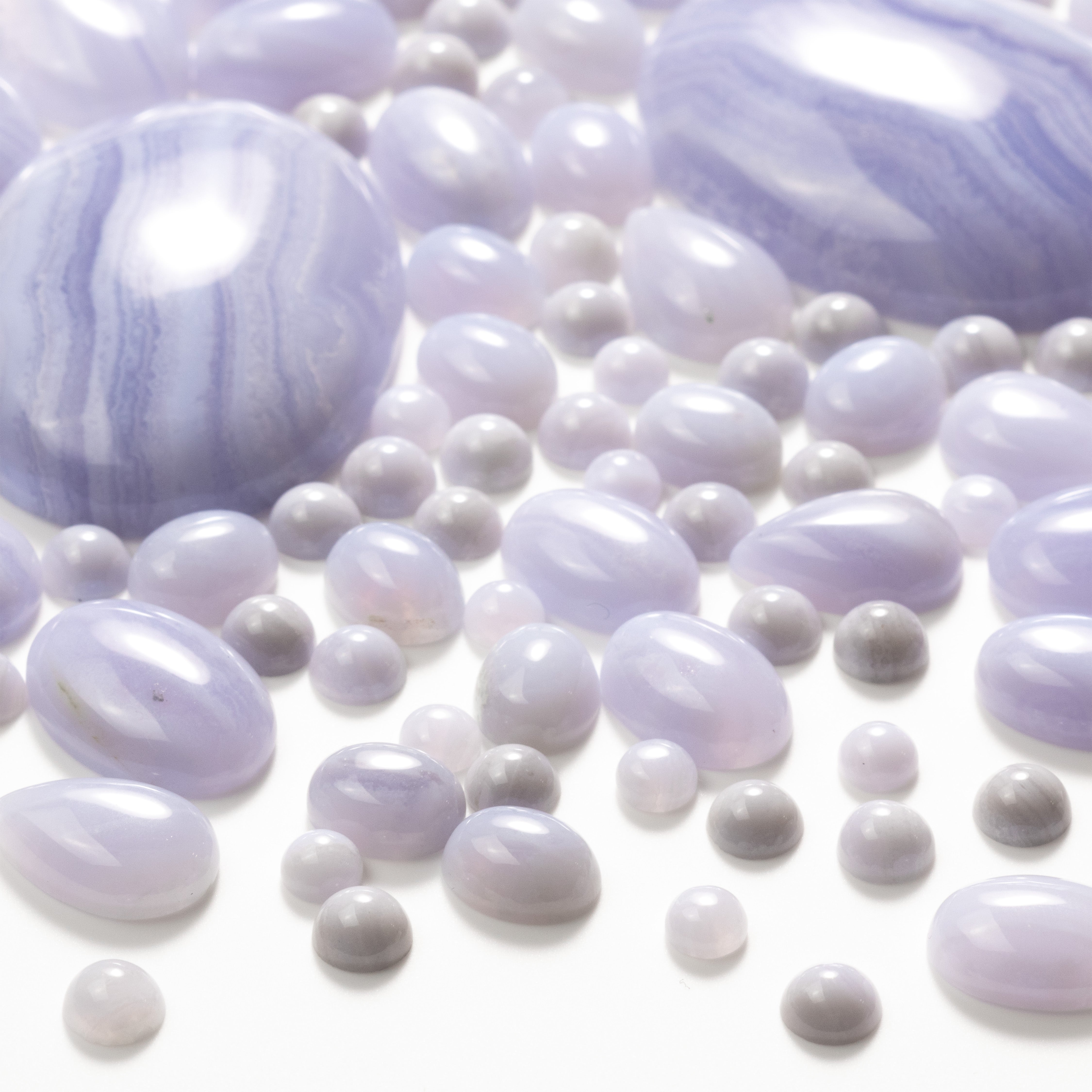 Blue lace agate cabochons, round and oval shapes, scattered on a white background