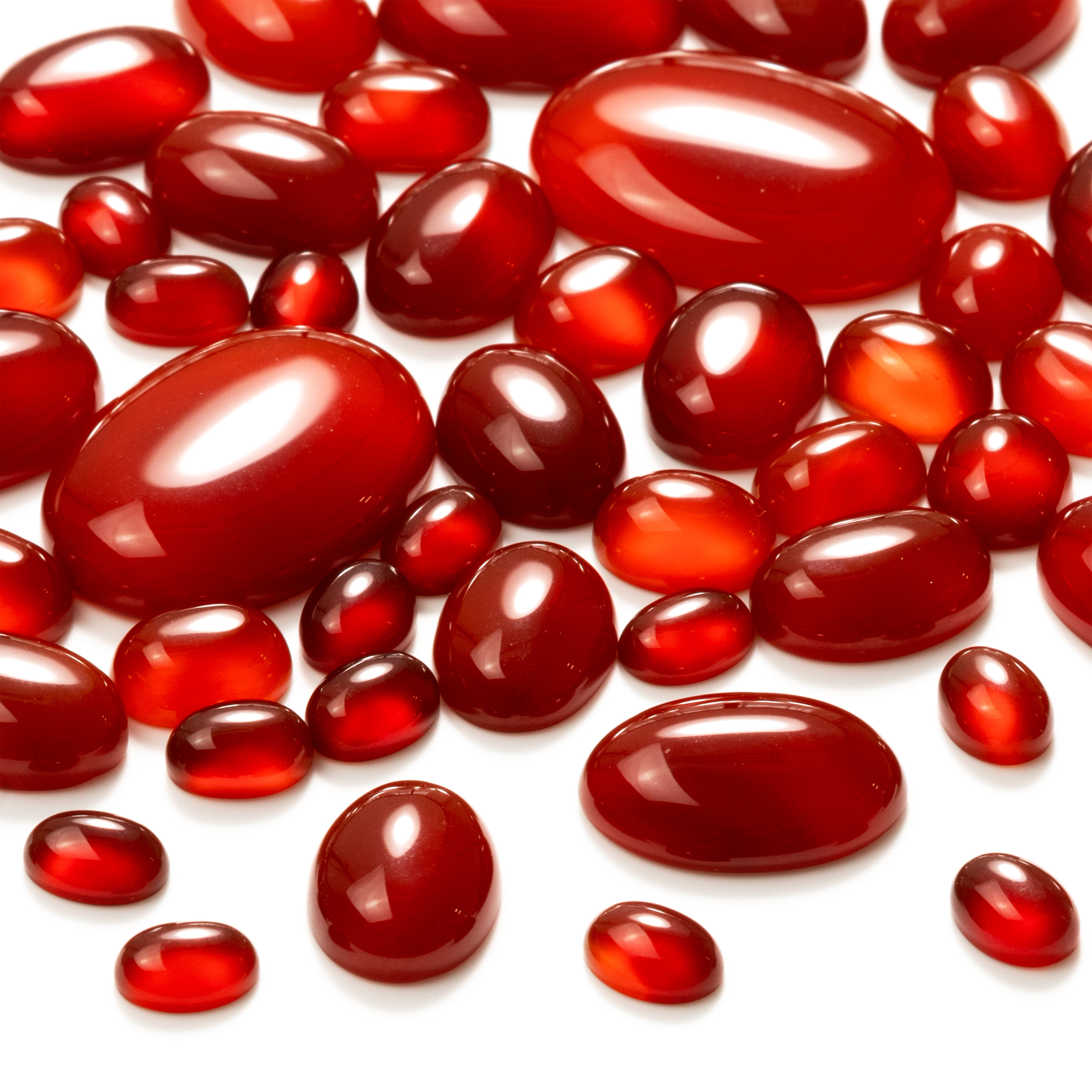 Carnelian oval cabochons scattered on a white background