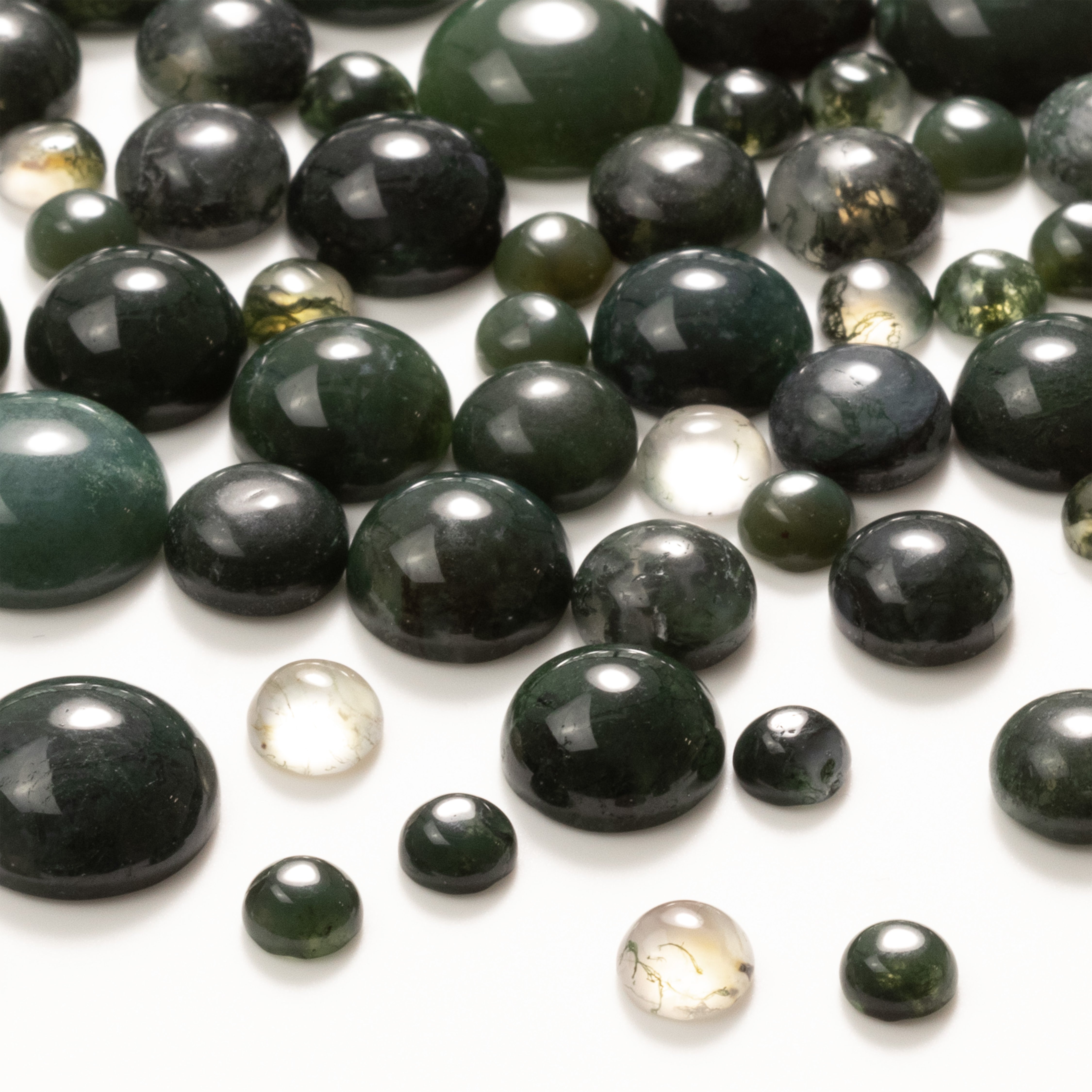 Green moss agate round cabochons, scattered on a white background